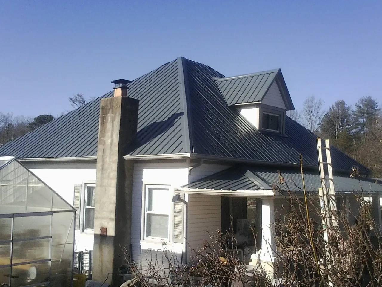 Dark blue standing seam metal roof on a white farmhouse with dormer — Slate & Tile Roof Repair by Roofing Brothers in Yale